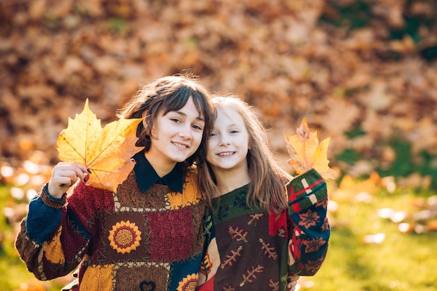 Due sorelle ragazze con foglie d'arancio autunnali Bellezza sana e naturale della donna Ragazza sorridente con