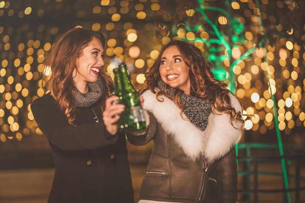 Due sorelle si godono la serata fuori e brindano con bottiglie di birra in mano.