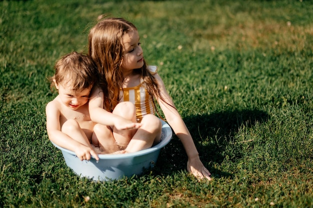 Due sorelle si sono arrampicate in una ciotola di acqua fresca in una giornata calda e si sono tuffate nell'acqua nel cortile di una casa del villaggio