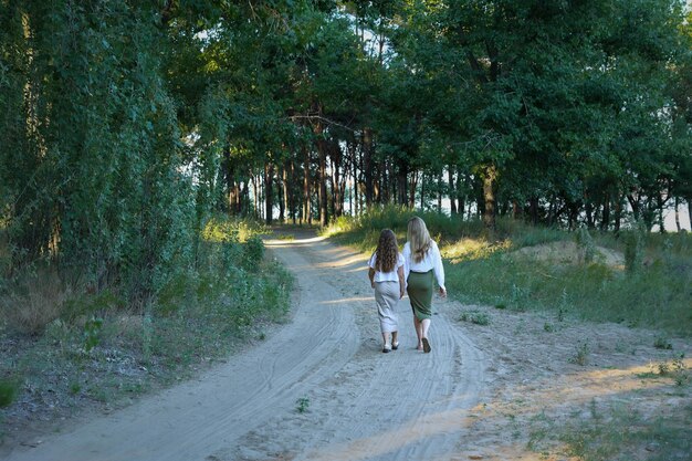 Due sorelle si tengono per mano, camminano lungo il sentiero in lontananza