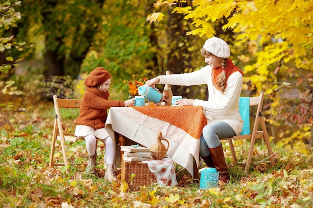 Due sorelle sveglie che bevono tè nel giardino di autunno