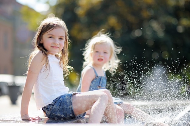 Due sorelline divertendosi in una fontana della città