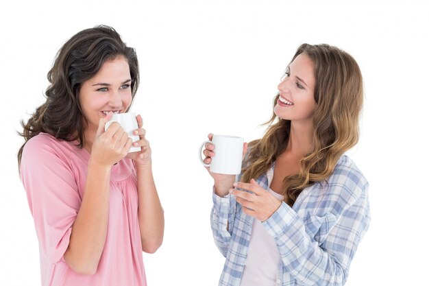 Due sorridenti giovani amici femminili che bevono caffè