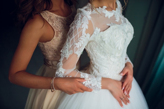 Due spose sussurrano qualcosa e ridono. Belle ragazze delicate in abiti da sposa.