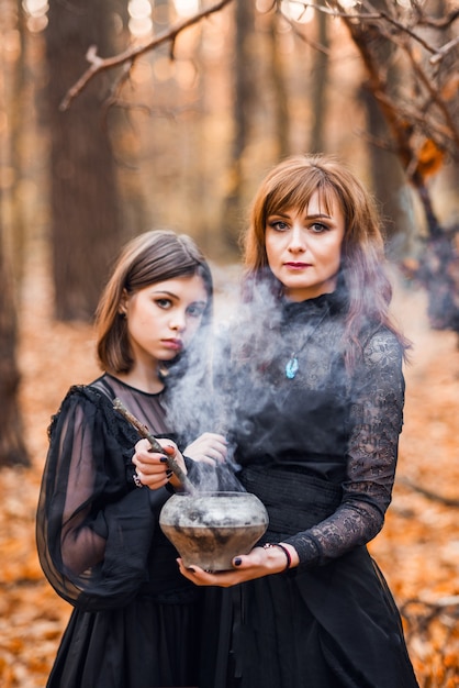 Due streghe nella foresta autunnale. Madre e figlia preparano una pozione.