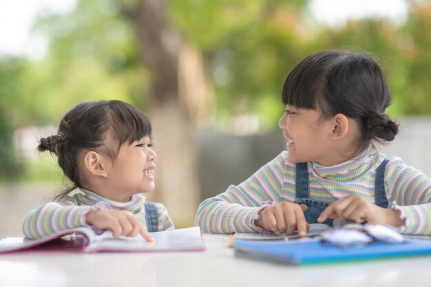 Due studentesse asiatiche che leggono il libro sul tavolo