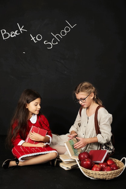 due studentesse belle amiche sedute con libri e un cesto di mele
