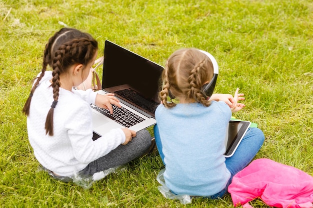 due studentesse divertenti si siedono sull'erba e leggono libri. Ragazze, fidanzate, sorelle ricevono lezioni in natura.