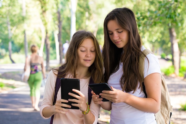 Due studentesse sorridenti con i tablet all'aperto