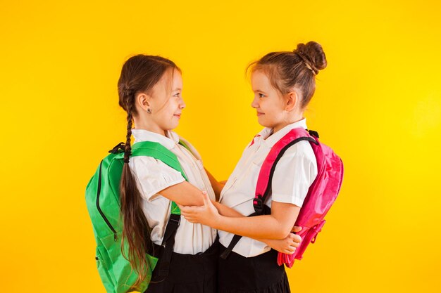 Due studentesse sorridenti in uniforme si stanno abbracciando al giallo