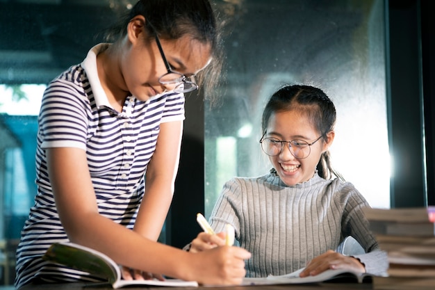 Due studenti asiatici leggendo un libro di scuola con emozione di felicità