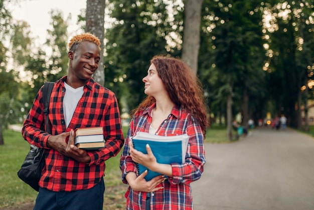 Due studenti camminano sul marciapiede nel parco estivo. Adolescenti bianchi maschi e femmine all'aperto