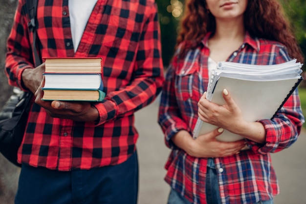 Due studenti camminano sul marciapiede nel parco estivo. Gli adolescenti bianchi maschi e femmine si rilassano all'aperto