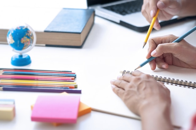 Due studenti che fanno i compiti e si aiutano a vicenda seduti in un tavolo nella sala di classe