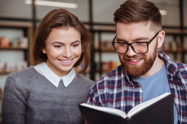 Due studenti felici che lavorano insieme in biblioteca con libri