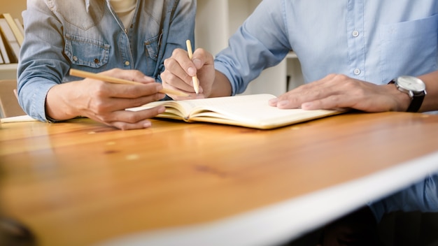 Due studenti fiduciosi facendo insieme insieme mentre si siedono in casa o nella stanza di classe