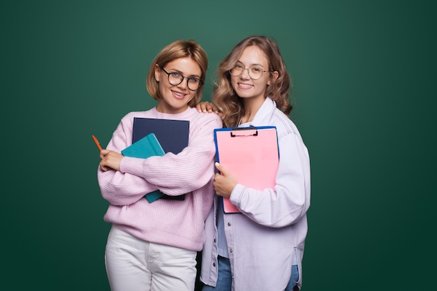 Due studenti in posa con alcune cartelle e sorridere alla telecamera indossando occhiali da vista