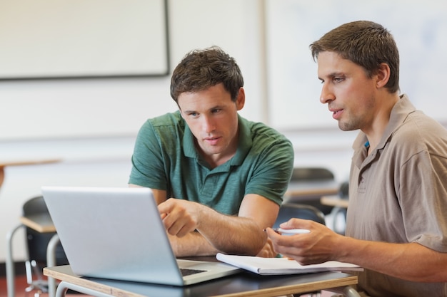 Due studenti maturi belli concentrati seduti in classe