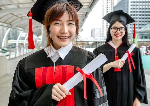 Due studenti universitari asiatici indossano abiti da donna in possesso di diploma di laurea