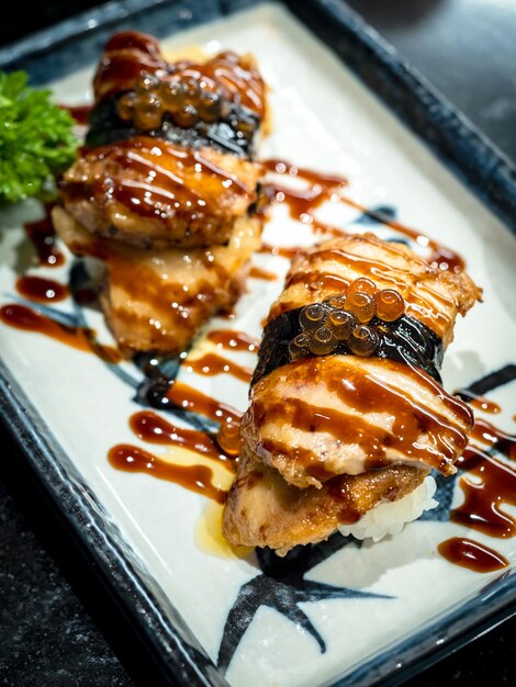 Due sushi di foie gras con salsa serviti su un piatto bianco su tavola scura in stile cibo giapponese Foie gras bruciato su riso giapponese con prugna acida in stile verticale