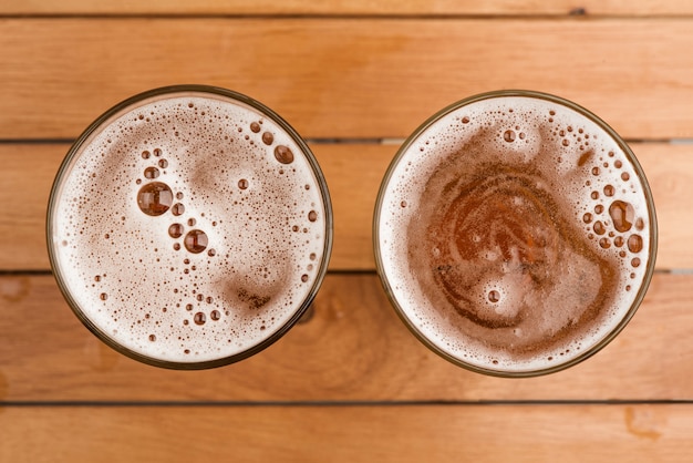 Due tazza di birra con la bolla su vetro sul fondo di legno di vista superiore