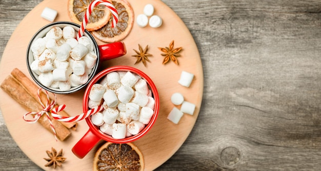 Due tazze con caffè e marshmallow anice cannella arance secche su un tavolo di legno