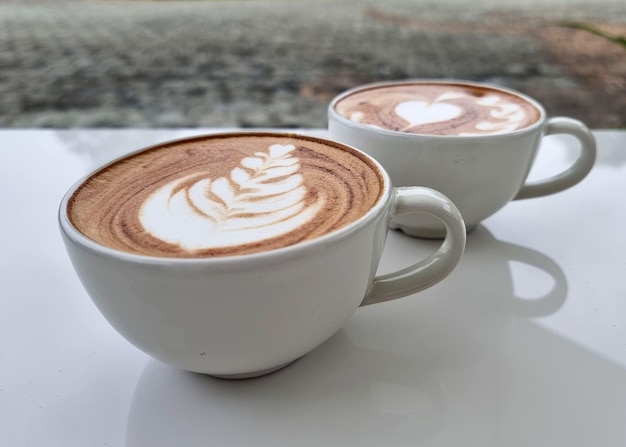 Due tazze di caffè caldo latte art su un tavolo bianco