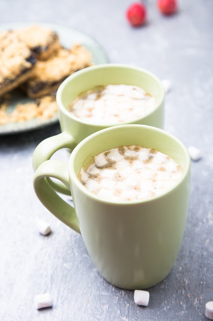 Due tazze di caffè caldo o cioccolato e torta con marshmallow