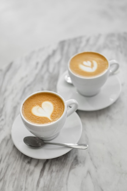 Due tazze di caffè con cake art su sfondo bianco