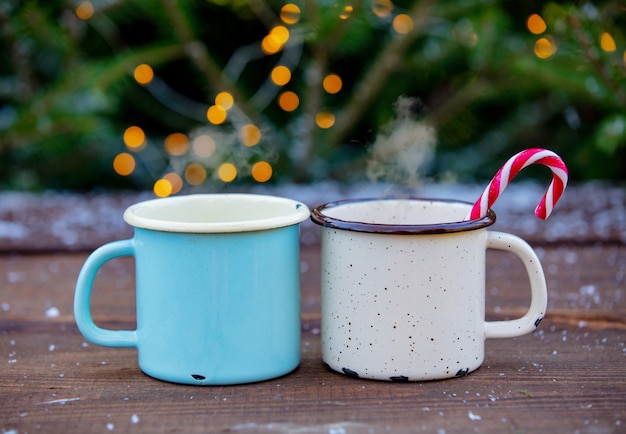 Due tazze di caffè con lucine e pino