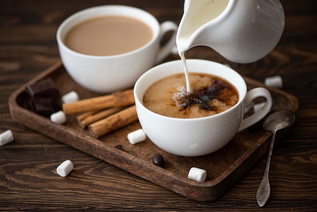 Due tazze di caffè nero con latte su un vassoio