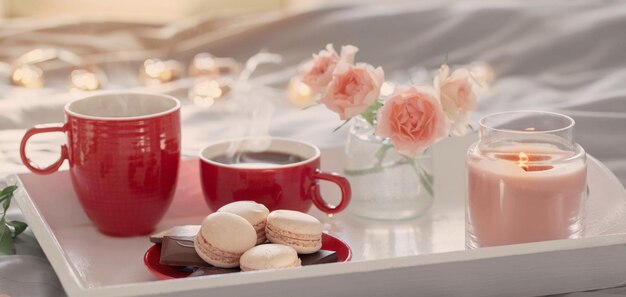 Due tazze di caffè rosse e fiori sul letto