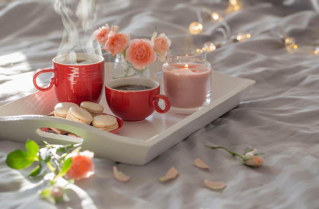 Due tazze di caffè rosse e fiori sul letto