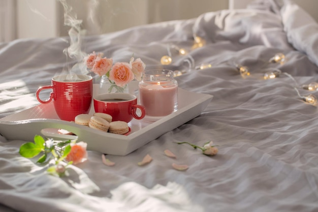 Due tazze di caffè rosse e fiori sul letto