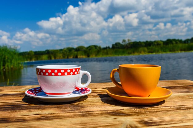 Due tazze di caffè su un tavolo di legno rustico in riva al fiume