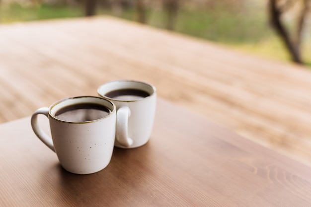 Due tazze di caffè sul tavolo sulla terrazza in legno marrone. Rilassamento, concetto di vita di campagna silenziosa