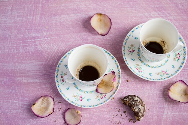 Due tazze di caffè vuote e petali di rosa