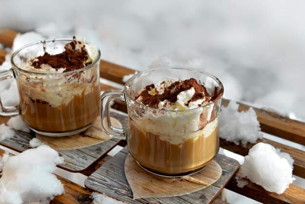 Due tazze di cappuccino poste su una slitta di legno in mezzo alla neve