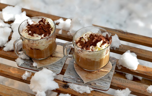 Due tazze di cappuccino poste su una slitta di legno in mezzo alla neve