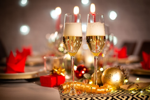 due tazze di champagne su un tavolo festivo per le vacanze di natale con decorazioni lucide rosse e dorate