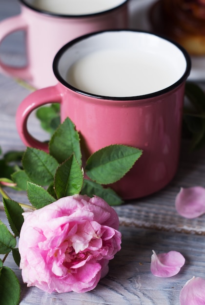 Due tazze rosa con latte sul tavolo di legno bianco