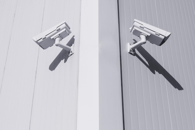 Due telecamere CCTV in diverse direzioni all'angolo dell'edificio per controllare gli oggetti