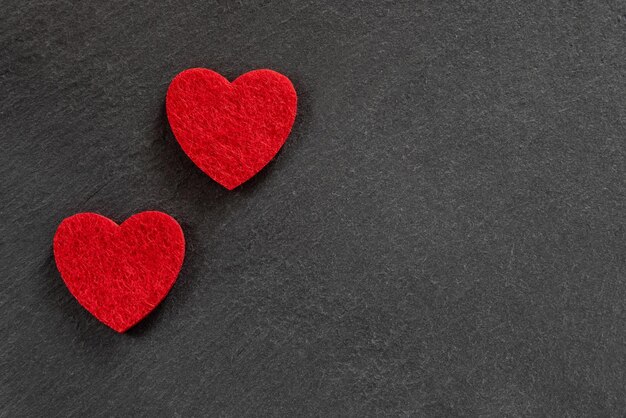 Due tessuti rossi a forma di cuore sullo sfondo nero della natura