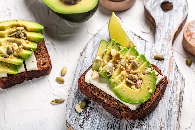 Due toast con avocado e formaggio guarniti con noci e sesamo per colazione o pranzo Cibo vegetariano Cibo pulito Vista dall'alto Copia spazio