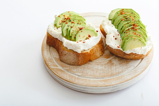 Due toast con avocado, panino con avocado. Avocado fresco affettato su toast di pane di grano, crema di formaggio.