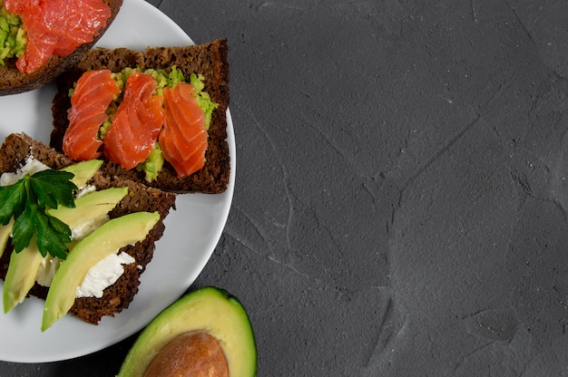 Due toast con fette di avocado con crema di formaggio e avocado smash con salmone pesce rosso