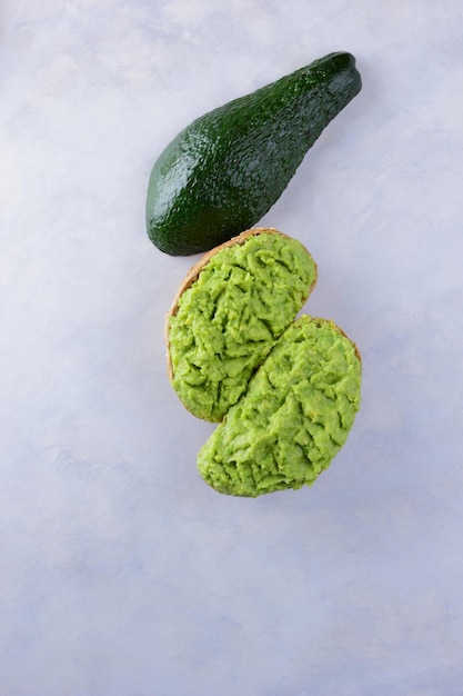 Due toast di avocado e mezzo avocado maturo fresco isolato su sfondo bianco Cibo sano per la colazione Concetto di cibo vegetariano Closeup Vista dall'alto