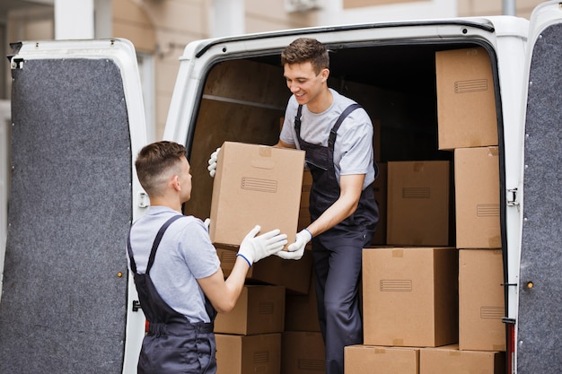 Due traslochi in divisa stanno scaricando il furgone pieno di scatole Servizio trasloco casa