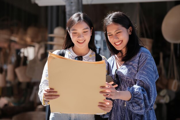 Due turisti asiatiche guardano le mappe di viaggio mentre percorrono la strada