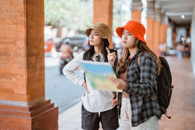 Due turisti asiatici guardano una mappa mentre si dirigono verso una destinazione turistica